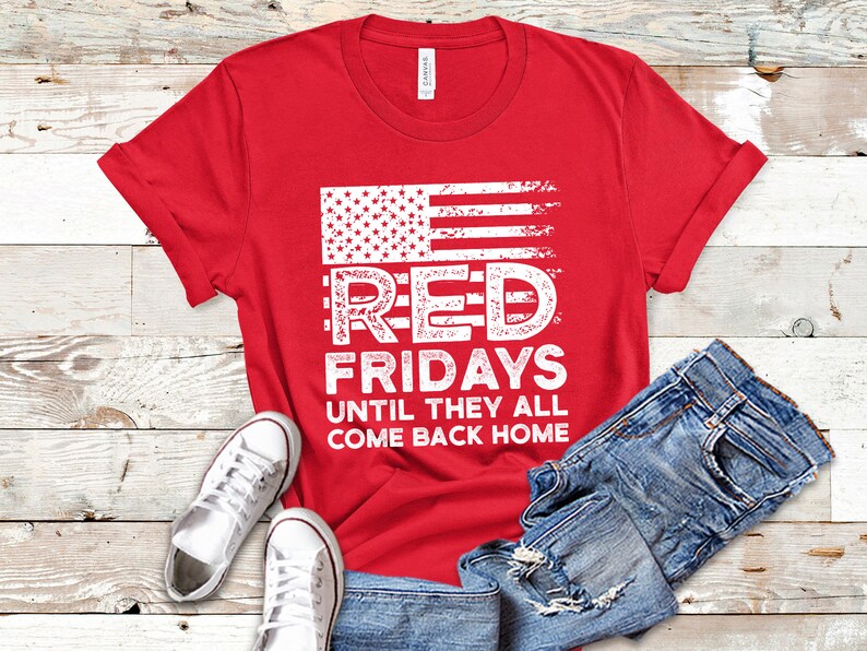 May include: Red t-shirt with a distressed American flag graphic and the text "Red Fridays Until They All Come Back Home".