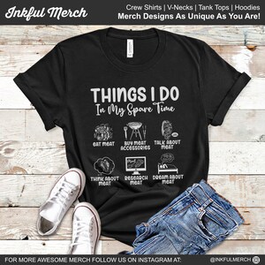 May include: Black t-shirt with white text that reads "Things I Do In My Spare Time". The shirt features a graphic with six illustrations of meat-related activities, including eating meat, buying meat accessories, talking about meat, thinking about meat, researching meat, and dreaming about meat.