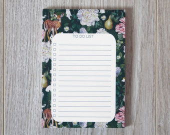 May include: A white to-do list notepad with a floral and deer design. The notepad has a green background with white, pink, and yellow flowers, a pear, and a deer.