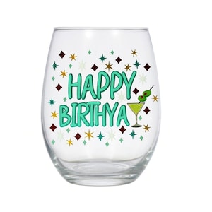 May include: A clear glass wine glass with a green and white design that says "Happy Birthya" with a martini glass and olives on the side.