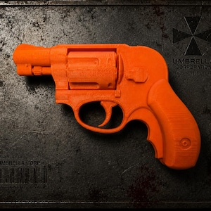May include: A bright orange toy revolver featuring a textured surface and a visible cylinder. The object is positioned against a dark, weathered metal plate displaying the Umbrella Corporation logo, text, and a barcode from Raccoon City, USA.