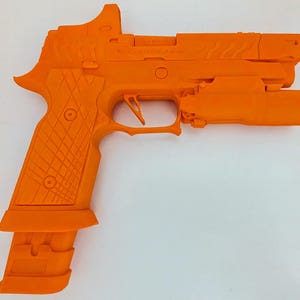 May include: Bright orange handgun with a mounted light and sight. The grip has a textured pattern, and the magazine is extended. The gun is a solid, single color, and appears to be a training or display model.