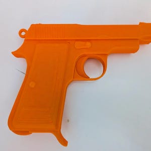 May include: Bright orange toy pistol. The toy gun is a replica of a handgun, featuring a trigger, grip, and barrel. The toy is made of plastic and is a solid, uniform color. The pistol is set against a white background.
