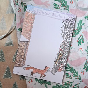 May include: A white card with a winter scene featuring a red fox walking in the snow. The card has a brick chimney on the left and a snowy evergreen tree on the right. The text "Winter Wishes" is written across the top of the card. The card is signed "Kerry Diks".
