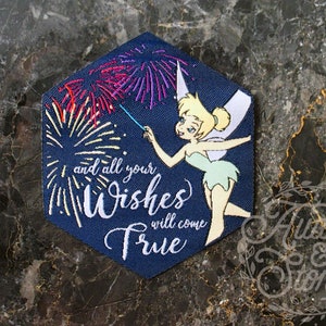 Pu&ograve; includere: Una toppa esagonale blu con un personaggio di Trilly che tiene una bacchetta magica con fuochi d'artificio. Il testo sulla toppa recita "and all your Wishes will come True".