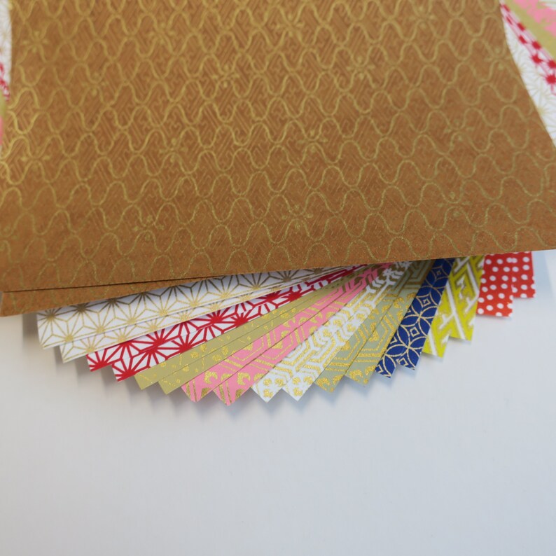 Puede incluir: Una pila de papel de origami con patrones coloridos con una hoja de patr&oacute;n marr&oacute;n en la parte superior. El papel tiene una variedad de dise&ntilde;os geom&eacute;tricos y florales.
