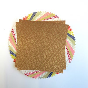 Puede incluir: Una pila de papel de origami con patrones coloridos con una sola hoja de papel dorado con un patr&oacute;n repetitivo en la parte superior.