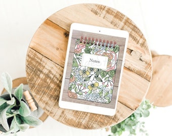 May include: A white tablet with a floral patterned notebook cover. The cover has a pink, green, and yellow floral design with the word "Notes" written on it.