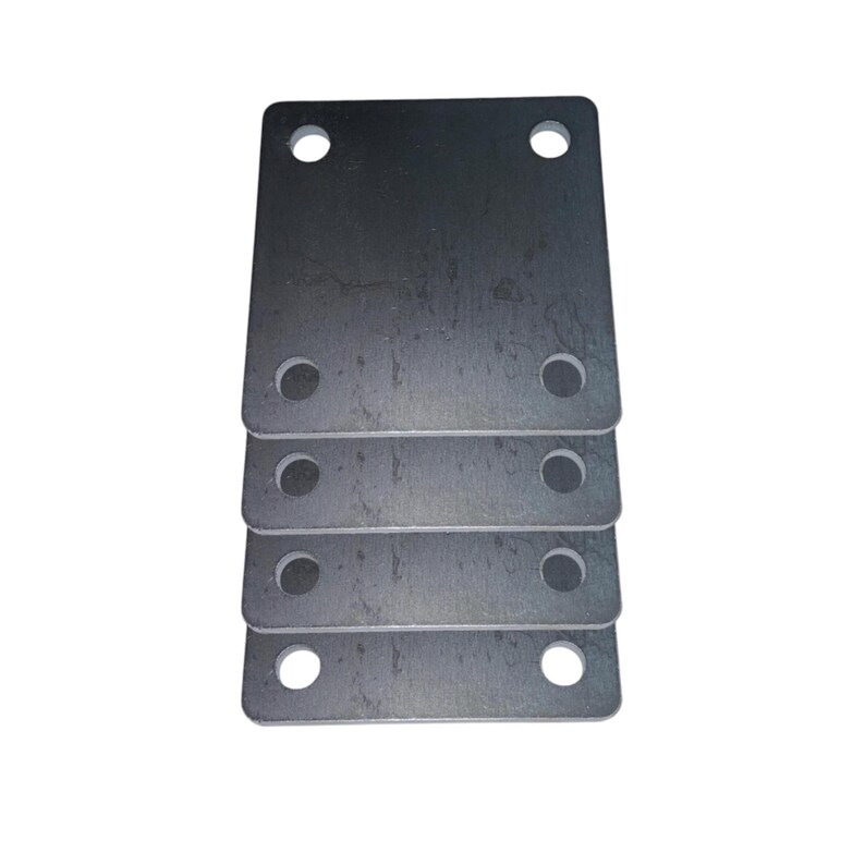 May include: A stack of four rectangular metal plates with rounded corners. Each plate has two small holes on the top and two on the bottom. The metal has a dark, matte finish.