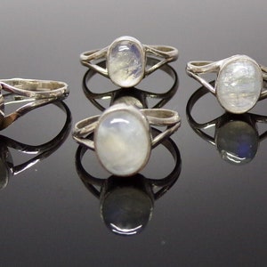 Puede incluir: Cuatro anillos de plata con piedras de luna ovaladas. Los anillos tienen un diseño delicado de banda retorcida.