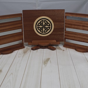 May include: Three wooden display stands with a Celtic knot design on the center stand. The stands have a brown wood finish and silver metal accents.