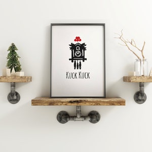 May include: A black and white illustration of a cuckoo clock with red berries on top. The clock is on a white background with the text "KUCK KUCK" underneath. The illustration is framed and hanging on a wall with two wooden shelves on either side.