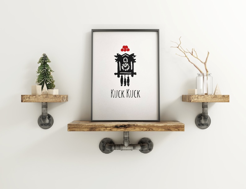 May include: A black and white illustration of a cuckoo clock with red berries on top. The clock is on a white background with the text "KUCK KUCK" underneath. The illustration is framed and hanging on a wall with two wooden shelves on either side.
