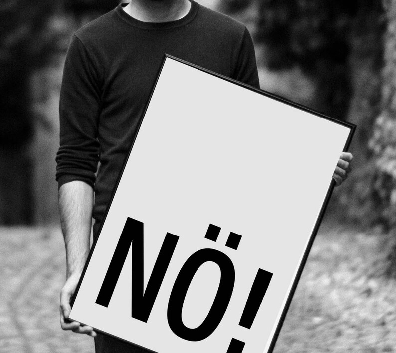 May include: A black and white image of a person holding a poster with the word "N&Ouml;!" printed in bold, black letters.