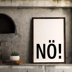 May include: A black and white framed print with the word "N&Ouml;!" in bold, black letters on a white background. The print is hanging on a gray concrete wall.