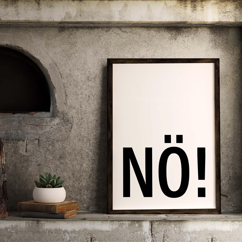May include: A black and white framed print with the word "N&Ouml;!" in bold, black letters on a white background. The print is hanging on a gray concrete wall.