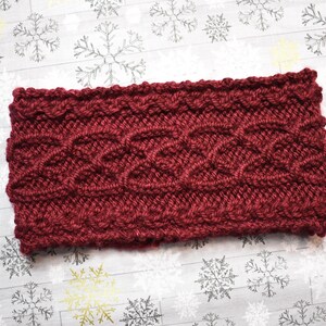 Puede incluir: Una diadema de punto color burdeos con un patrón de punto trenzado.