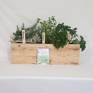 May include: A wooden planter box with four different herbs growing in it. The herbs are labeled "Rosemary", "Oregano", "Parsley", and "Oregano".