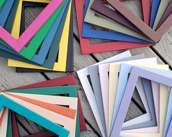 May include: A stack of colorful picture frames in various sizes and colors, including red, blue, green, yellow, and pink. The frames are made of wood and have a simple, modern design.