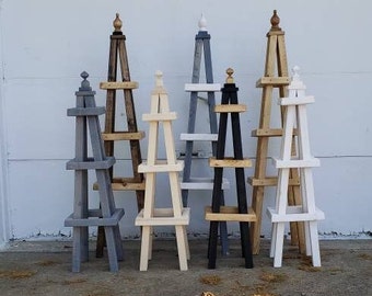 May include: A set of nine wooden plant stands in various colors and styles. The stands are made of wood and have a ladder-like design. They are all different heights and have different finishes.