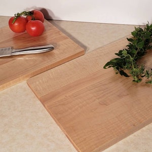 May include: Two wooden cutting boards, one with a knife and tomatoes, the other with fresh herbs.