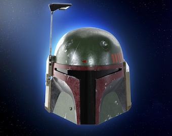 Puede incluir: Un casco de Boba Fett verde y marrón con una visera negra y una franja roja. El casco tiene un aspecto desgastado y está situado sobre un fondo azul oscuro con estrellas blancas.