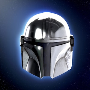 May include: A silver and blue Mandalorian helmet with a weathered finish. The helmet is set against a dark blue background with white stars.