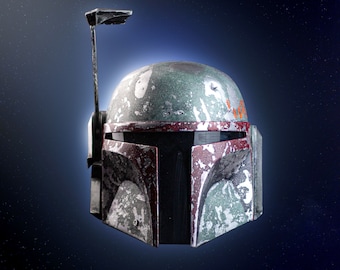 Puede incluir: Un casco de Boba Fett verde y rojo desgastado con una visera negra. El casco tiene una pequeña antena en la parte superior.