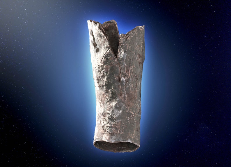May include: A silver-coloured, cylindrical, metal object with a rough, textured surface. The object is cracked and broken at the top. It is photographed against a dark blue background with white stars.