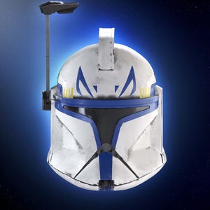 May include: A white and blue helmet with a visor, featuring blue markings and yellow accents. The helmet has a weathered appearance and a communication device attached. The design is reminiscent of a science fiction or military theme.