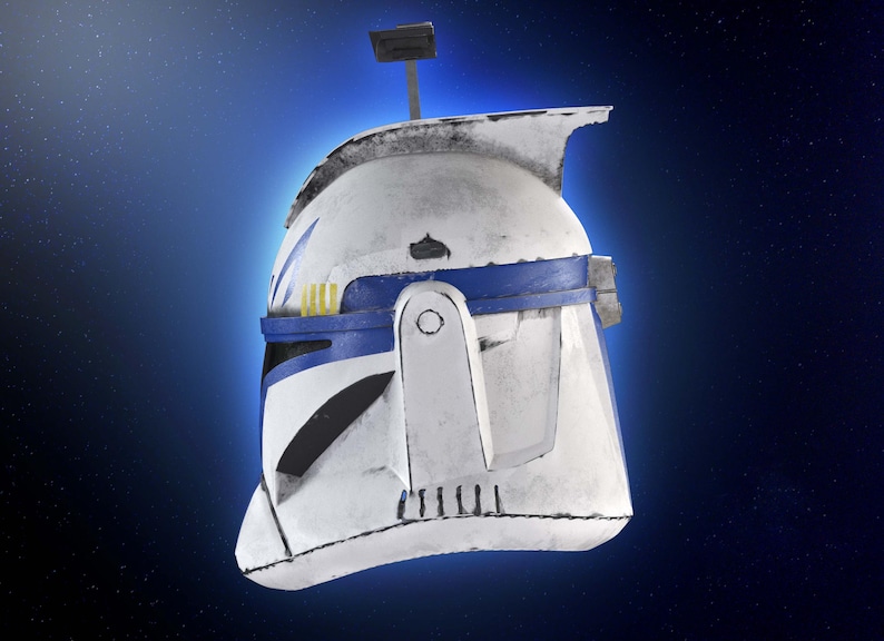 May include: A white and blue helmet with a weathered appearance, featuring a blue band and yellow accents. The helmet has a rectangular antenna and is set against a blue background with a starry effect. The helmet is a replica of a Star Wars clone trooper helmet.