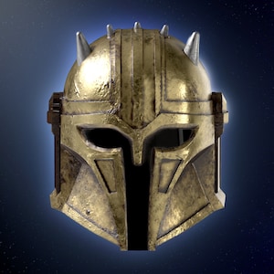 Könnte beinhalten: Ein goldener Helm mit schwarzem Visier und silbernen Spikes. Der Helm hat ein verwittertes, abgenutztes Aussehen.