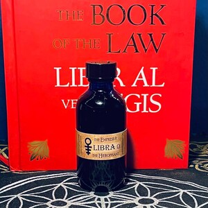 Puede incluir: Una peque&ntilde;a botella de vidrio azul oscuro con una tapa negra. La botella est&aacute; llena de un l&iacute;quido oscuro. La etiqueta de la botella es marr&oacute;n y tiene el texto "The Empress & Libra &Omega; The Hierophant".