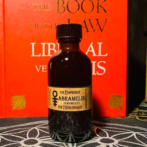 Puede incluir: Una botella de vidrio marr&oacute;n oscuro con una tapa negra, que contiene un l&iacute;quido oscuro. La etiqueta dice "The Empress & Abramelin (Crowley) The Hierophant".