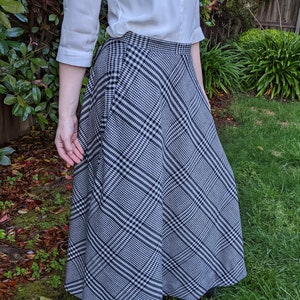 May include: A black and white plaid skirt with a flared silhouette. The skirt is knee-length and has a simple design.