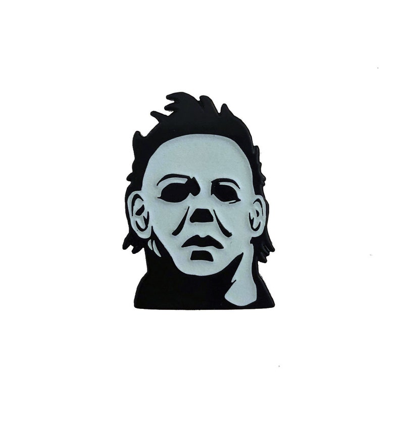 May include: Black and white enamel pin featuring a close-up of Michael Myers' mask from the Halloween horror film franchise.