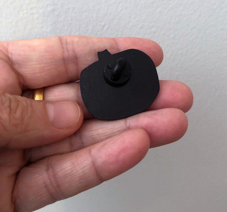 May include: Black enamel pumpkin pin with a silver pin back.