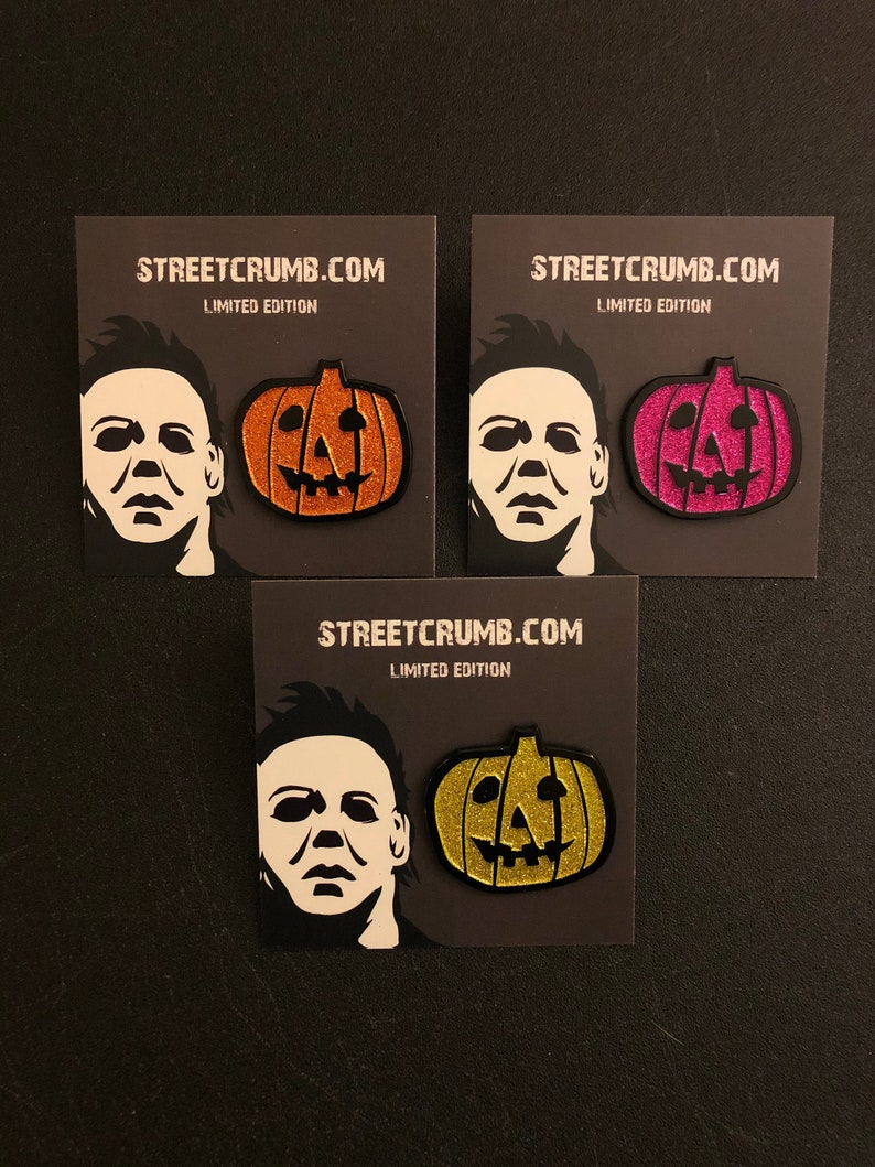 May include: Three black cards with the text "STREETCRUMB.COM LIMITED EDITION" printed on them. Each card features a black and white silhouette of Michael Myers from the Halloween franchise and a glitter pumpkin. The pumpkins are orange, pink, and gold.