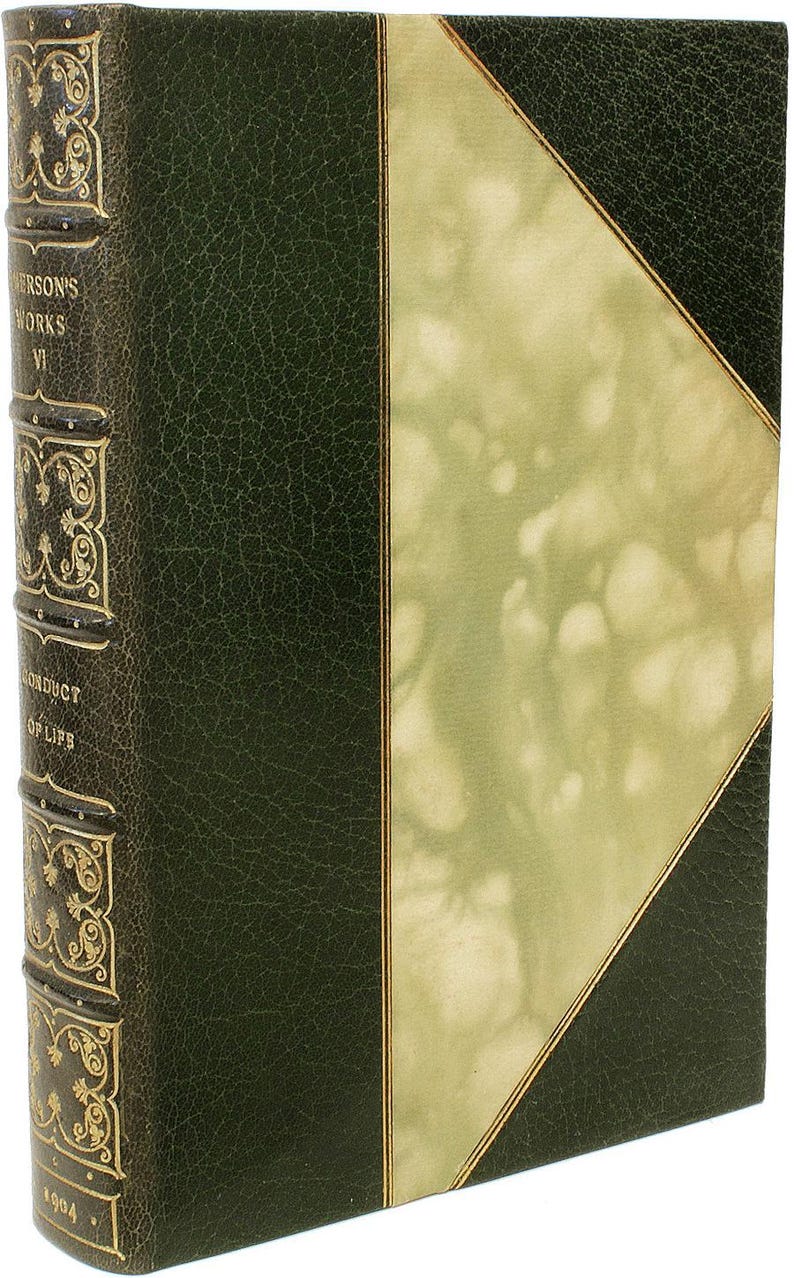 Puede incluir: Libro antiguo con cubierta de cuero verde oscuro y detalles dorados. La columna vertebral presenta texto en relieve y elementos decorativos. La portada tiene un dise&ntilde;o verde claro y dorado. El libro se titula "Emerson's Works VI" y "Conduct of Life".
