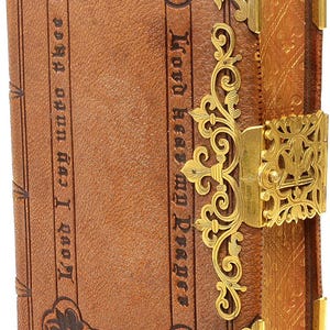 Puede incluir: Libro antiguo encuadernado en cuero con detalles met&aacute;licos dorados. La portada presenta texto en relieve y esquinas decorativas. El libro tiene un cierre y filigranas ornamentadas. El texto de la portada dice "Lord hear my Prayer" y "Watch".