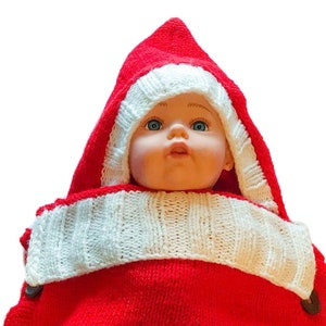 May include: A red knitted baby outfit with a white trim and a hood. The outfit has a button closure on the side.