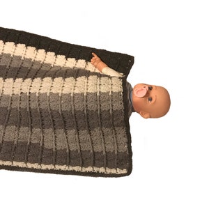 May include: A gray, white, and black striped crocheted baby blanket. The blanket is made with a textured stitch and has a dark gray border.