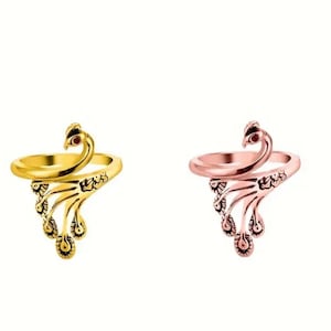 May include: Two peacock rings, one gold and one rose gold. The rings are adjustable and feature a detailed peacock design with a red stone eye.