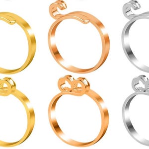 Op de afbeelding: Zes gouden ringen met een eenvoudig ontwerp. Drie ringen zijn goud, drie zijn zilver en alle hebben een klein strikje.