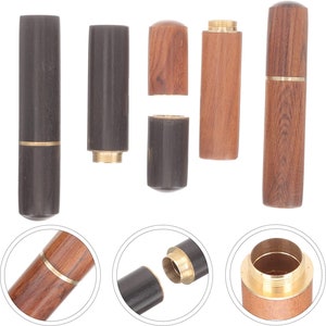 May include: Wooden toothpick holders in various stages of assembly. The holders are cylindrical, with a dark brown or light brown wood finish. Some have brass accents. The holders are shown both assembled and disassembled.