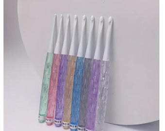 May include: Set of eight colorful crochet hooks with white handles. The hooks are made of clear plastic with a textured finish. The sizes of the hooks are labeled on the handles: 2.0 mm, 2.5 mm, 3.0 mm, 3.5 mm, 4.0 mm, 4.5 mm, 5.0 mm, and 5.5 mm.