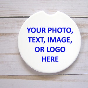 Op de afbeelding: Ronde witte keramische onderzetter met blauwe tekst die "YOUR PHOTO, TEXT, IMAGE, OR LOGO HERE" zegt.
