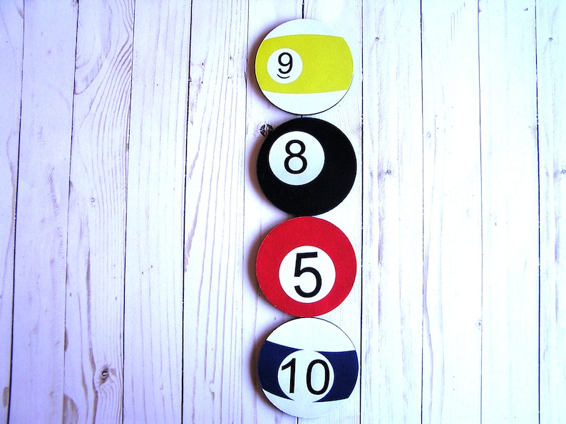 May include: Four billiard balls in a vertical row on a white wooden background. The balls are numbered 9, 8, 5, and 10. The balls are yellow, black, red, and blue.
