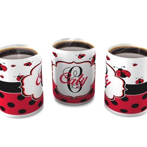 May include: Three white ceramic mugs with black and red ladybug designs. The mugs have black handles and are filled with coffee. The mugs have the letter "O" and the word "Caty" printed on them.