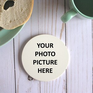 May include: White round coaster with the text "YOUR PHOTO PICTURE HERE" printed in black.